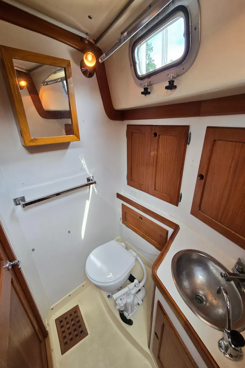 Slide: The Image of Compact 1984 Bristol 31.1 boat bathroom with wooden cabinets, mirror, and stainless steel sink. - 27