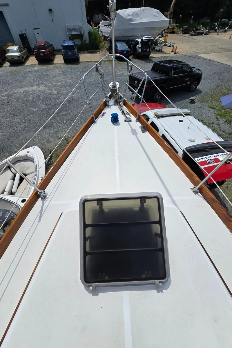 Slide: The Image of Bow view of 1984 Bristol 31.1 sailboat in a marina with parked vehicles. - 33