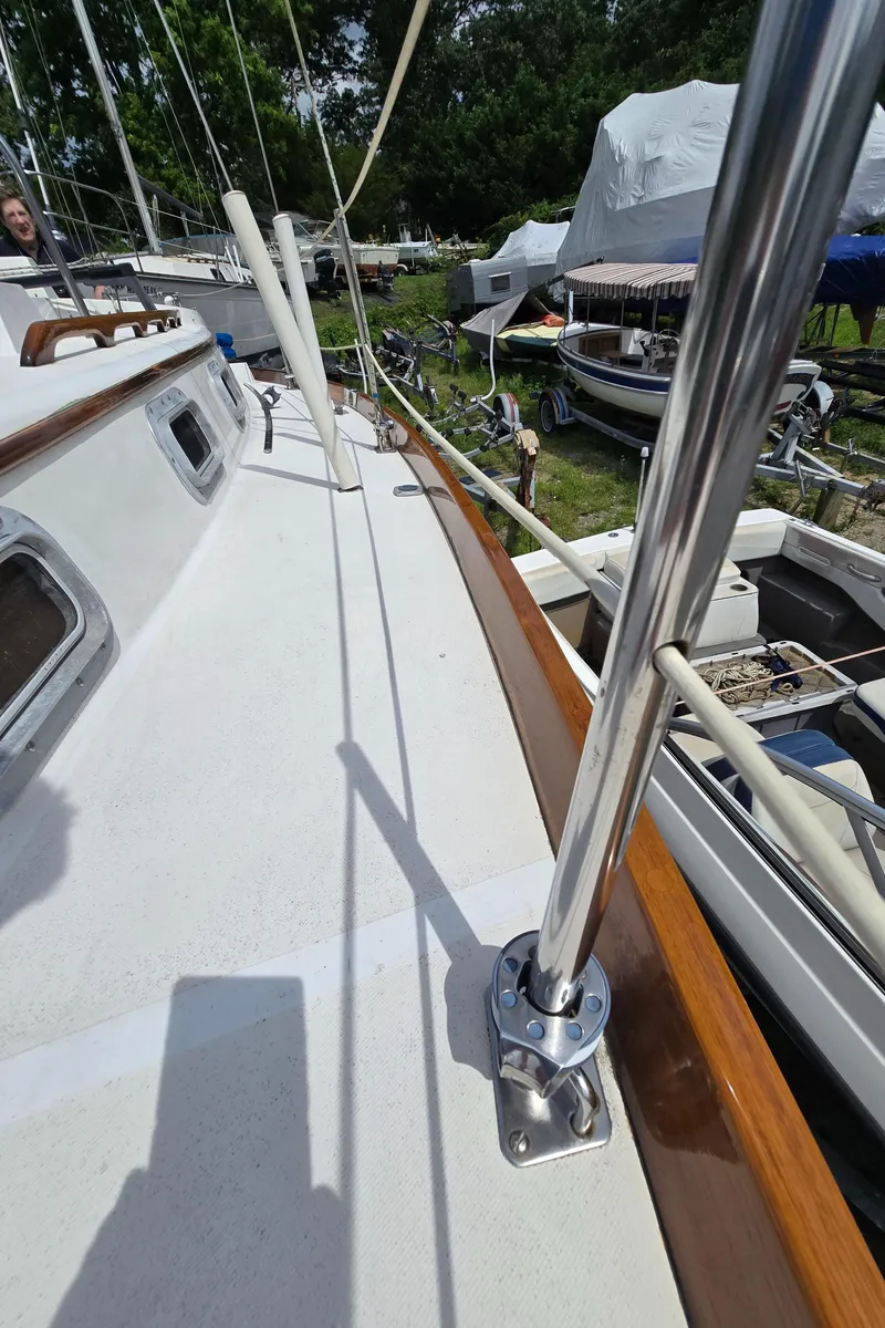 Slide: The Image of 1984 Bristol 31.1 sailboat deck with polished metal railings and wooden trim in a boatyard. - 35