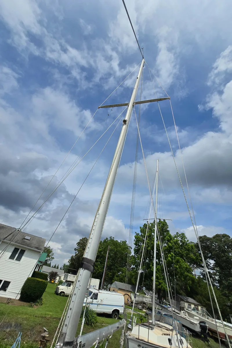 Slide: The Image of Sailboat mast of 1984 Bristol 31.1 against a cloudy sky in a residential area. - 36