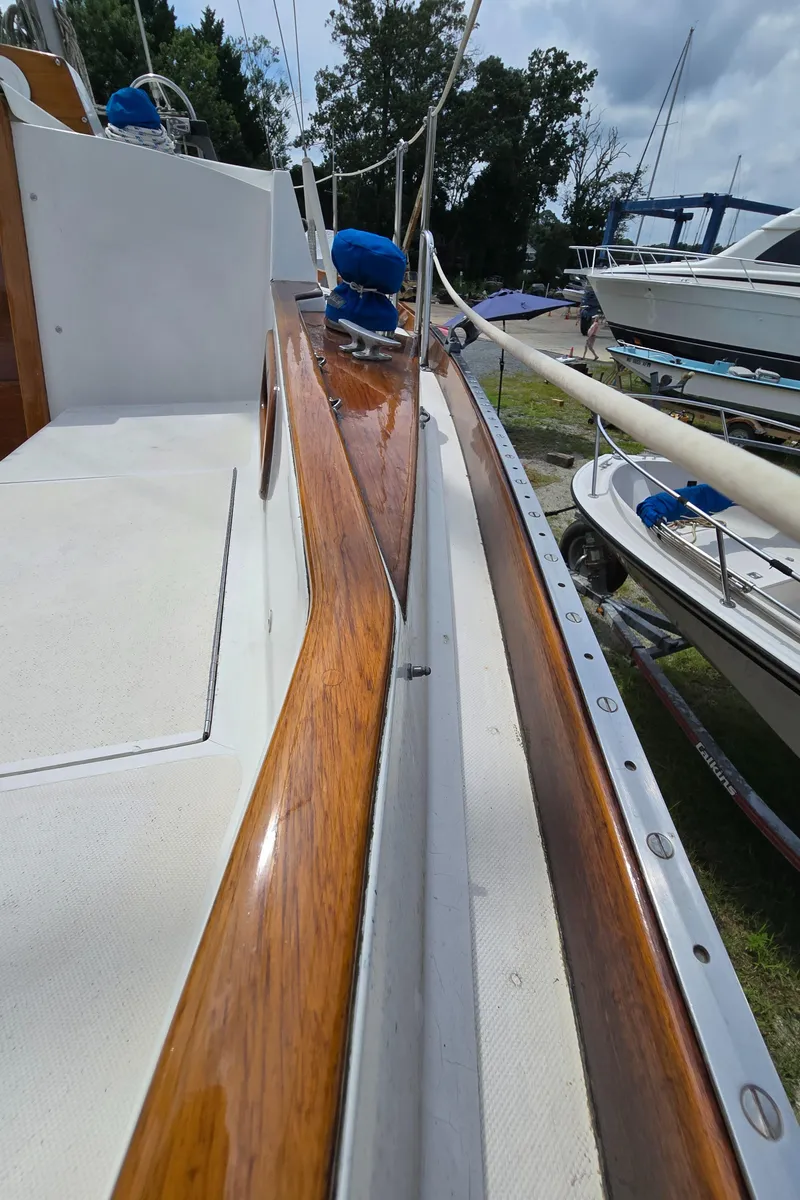 Slide: The Image of 1984 Bristol 31.1 sailboat deck with polished wood and white surface, docked outdoors. - 38