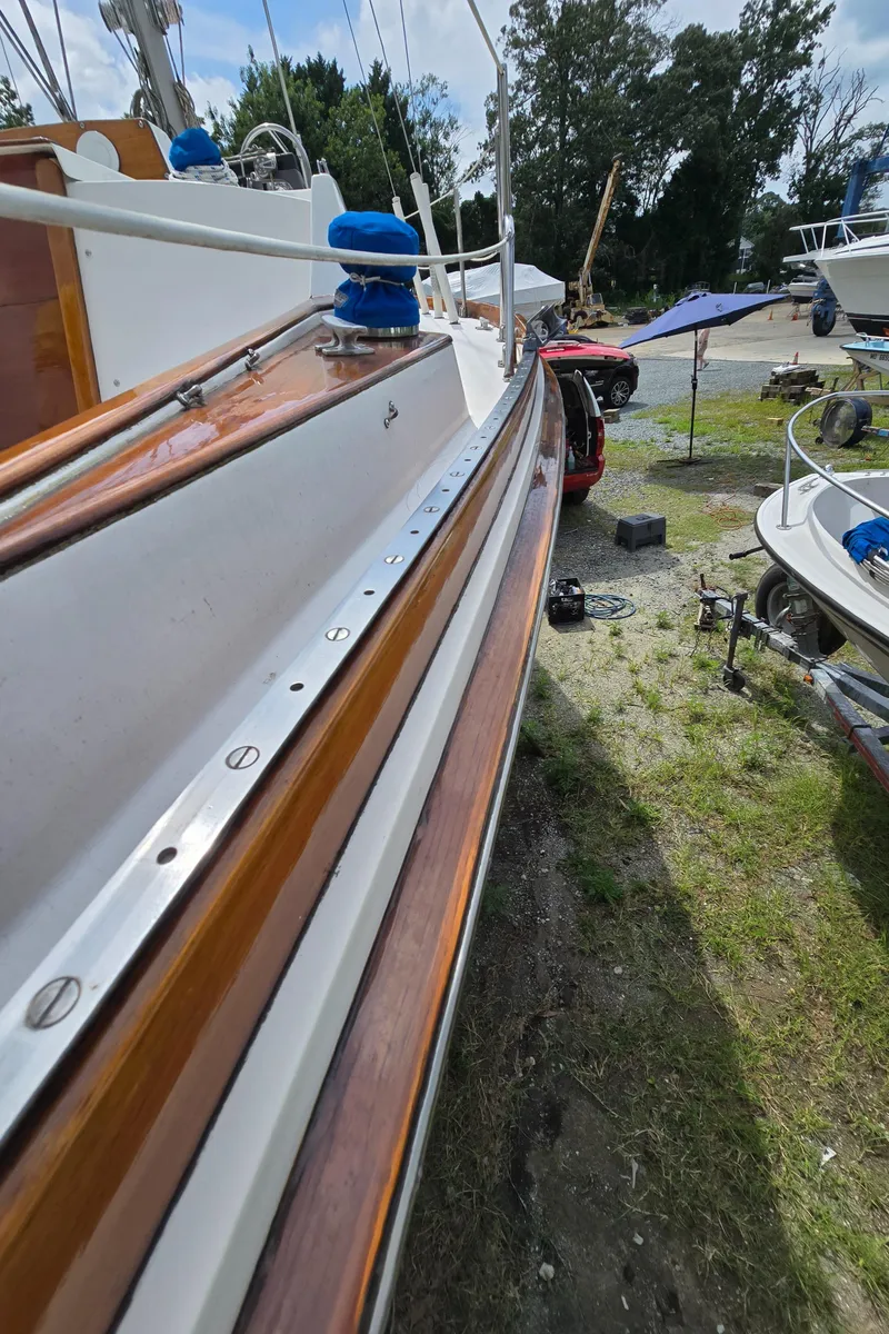 Slide: The Image of 1984 Bristol 31.1 sailboat with wooden trim, docked outdoors, surrounded by other boats. - 39