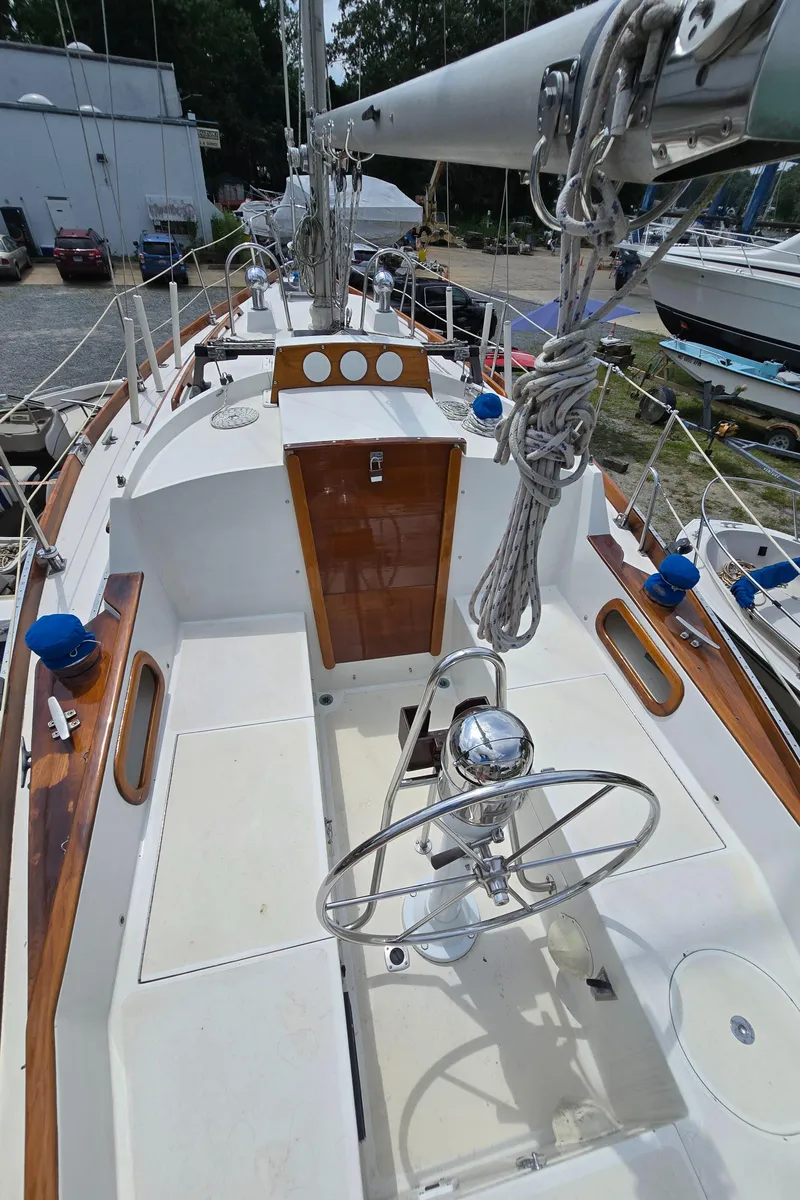 Slide: The Image of 1984 Bristol 31.1 sailboat deck with steering wheel and rigging, docked at a marina. - 43