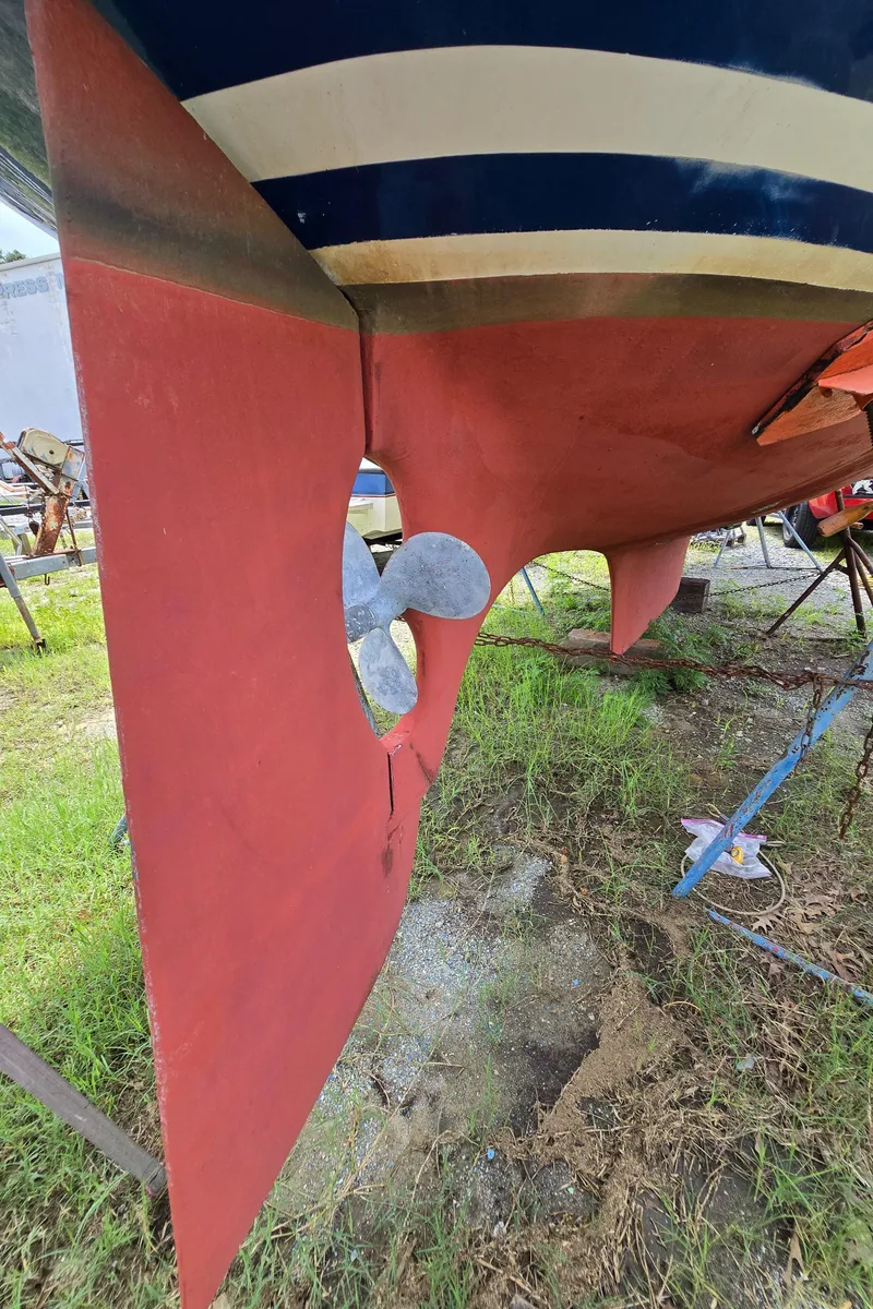 Slide: The Image of 1984 Bristol 31.1 sailboat hull and propeller, red and blue colors, on grassy ground. - 44
