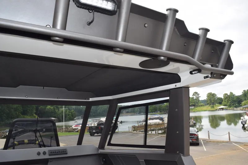 Slide: The Image of 2026 Stabicraft 1850 Supercab Sportfish interior with rod holders, overlooking a serene lakeside marina. - 9