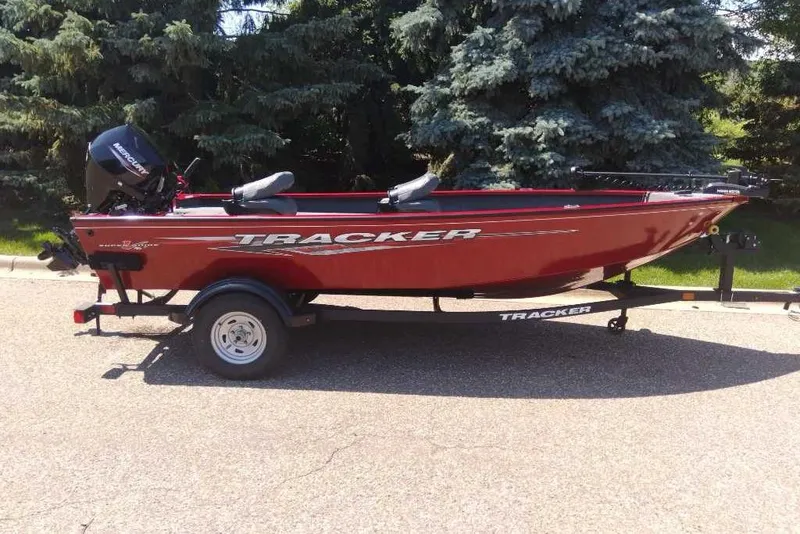 The Image of 2025 Tracker Super Guide V-16 T boat on trailer, red color, parked outdoors. - 0
