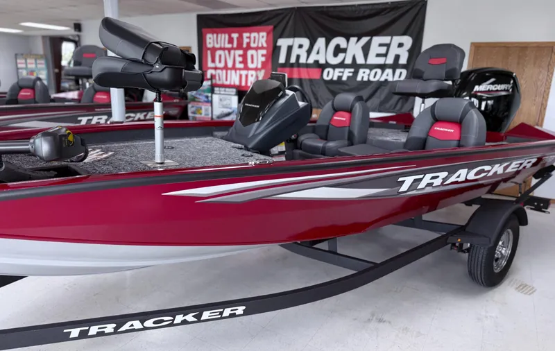 Slide: The Image of 2025 Tracker Pro Team 175 boat in showroom, red and black design, with Mercury engine. - 2
