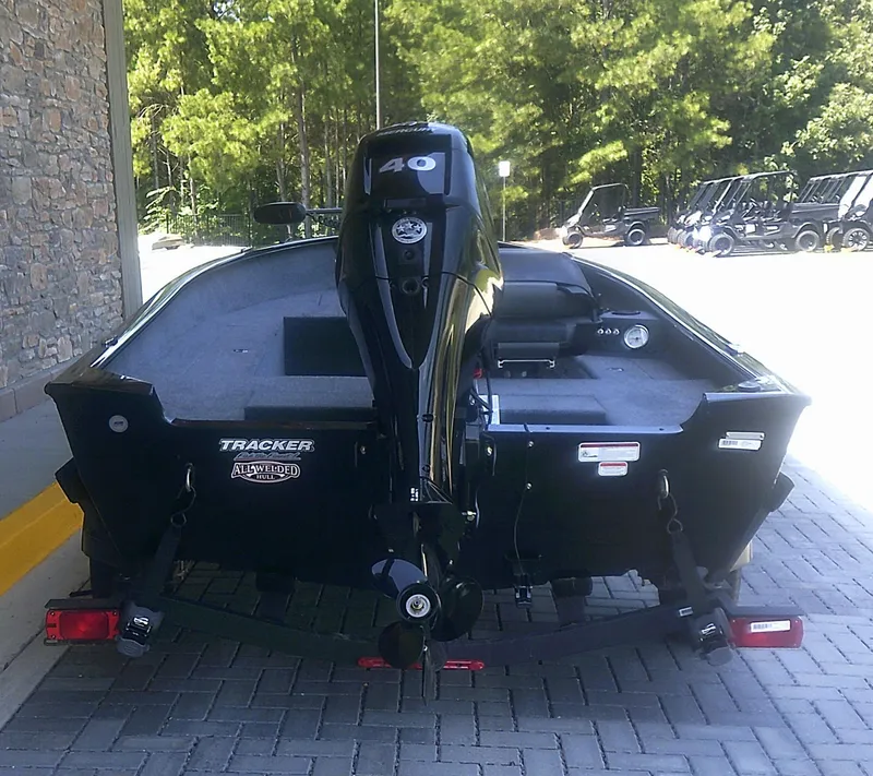 Slide: The Image of 2025 Tracker Super Guide V-16 T boat with 40 HP engine, parked on pavement. - 2