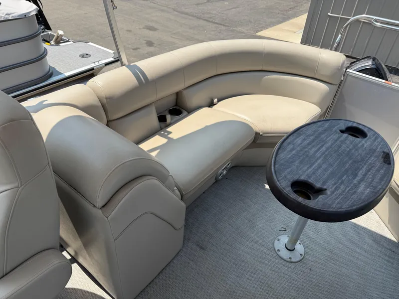 Slide: The Image of 2016 South Bay 521RS pontoon boat interior with beige seating and round table. - 13