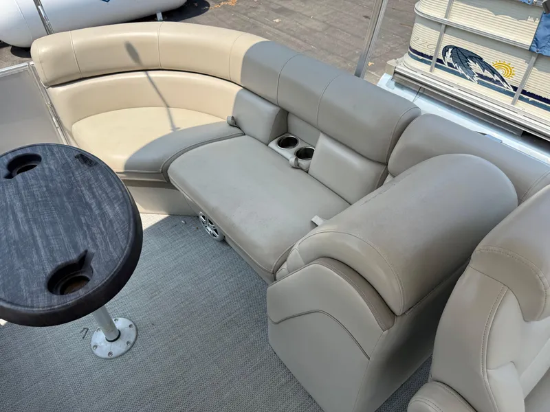 Slide: The Image of 2016 South Bay 521RS pontoon boat interior with beige seating and a round table. - 14
