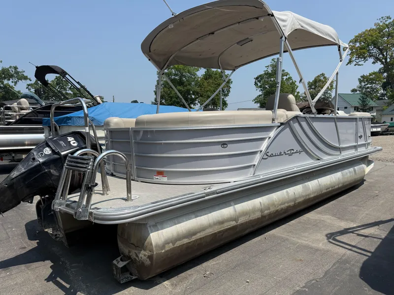 Slide: The Image of 2016 South Bay 521RS pontoon boat with canopy and outboard motor, parked on pavement. - 3