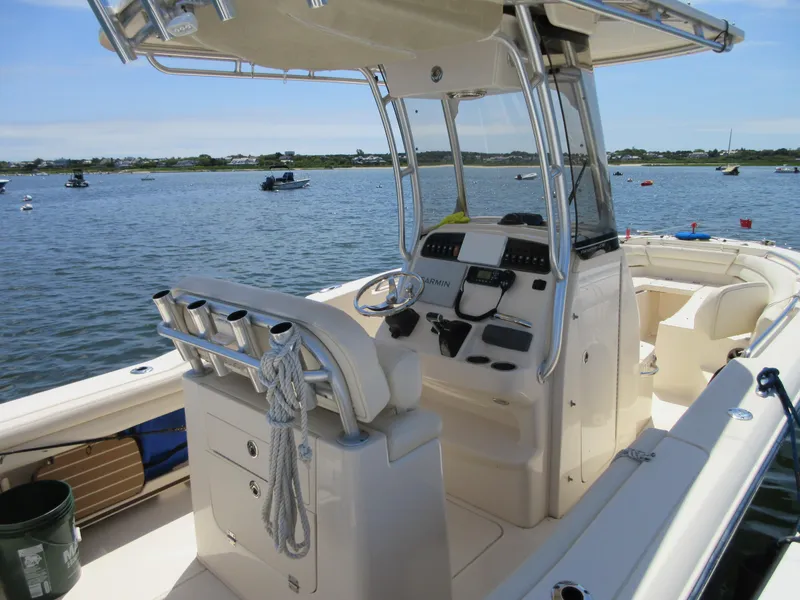 Slide: The Image of 2019 Grady-White Fisherman 236 boat interior with helm, rod holders, and seating on calm water. - 16