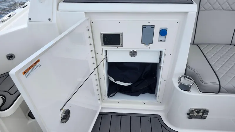 Slide: The Image of 2023 Pursuit OS 325 Offshore boat storage compartment with open door and seating area. - 22