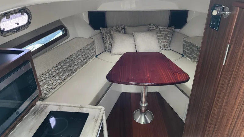 Slide: The Image of 2023 Pursuit OS 325 Offshore cabin interior with seating, table, and kitchenette. - 23