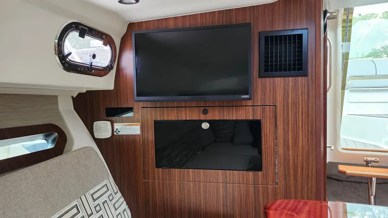 Slide: The Image of 2023 Pursuit OS 325 Offshore cabin interior with TV and wood paneling. - 29
