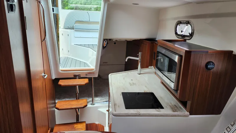 Slide: The Image of 2023 Pursuit OS 325 Offshore interior with modern kitchen and wooden accents. - 32