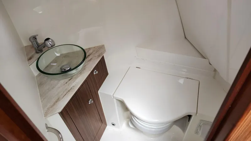 Slide: The Image of 2023 Pursuit OS 325 Offshore boat bathroom with glass sink and compact toilet. - 33