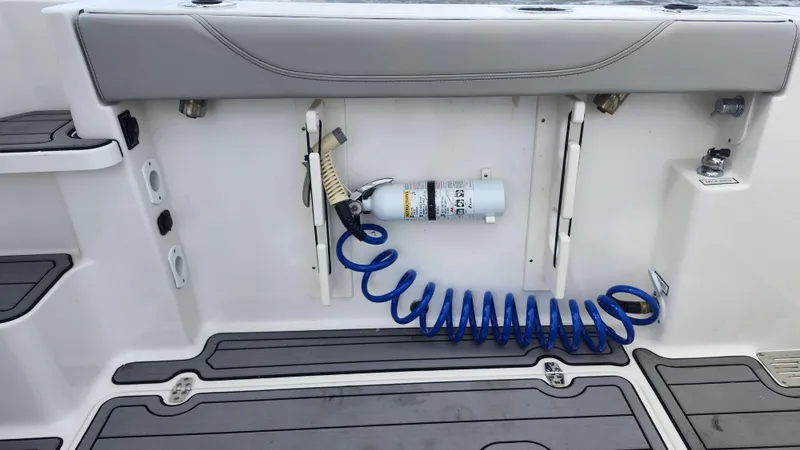 Slide: The Image of 2023 Pursuit OS 325 Offshore boat deck with coiled blue hose and storage compartments. - 43