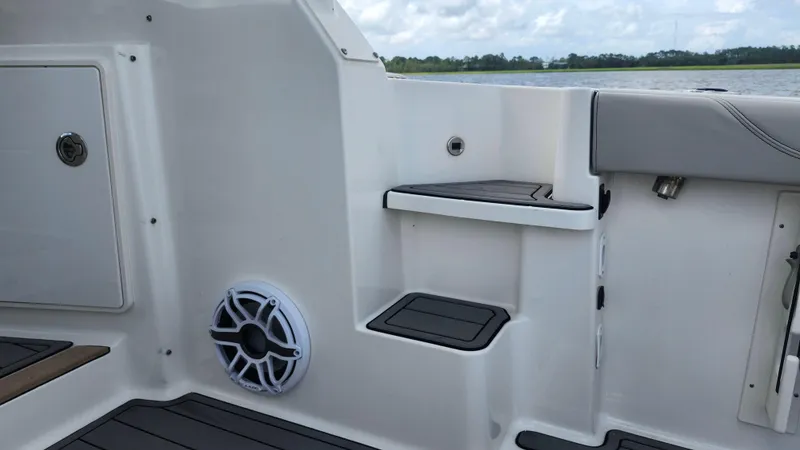 Slide: The Image of 2023 Pursuit OS 325 Offshore boat interior with steps and speaker, docked by water. - 9