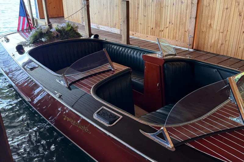 Slide: The Image of 1997 Hacker-Craft 26' Runabout with elegant wood finish and American flag in a boathouse. - 14