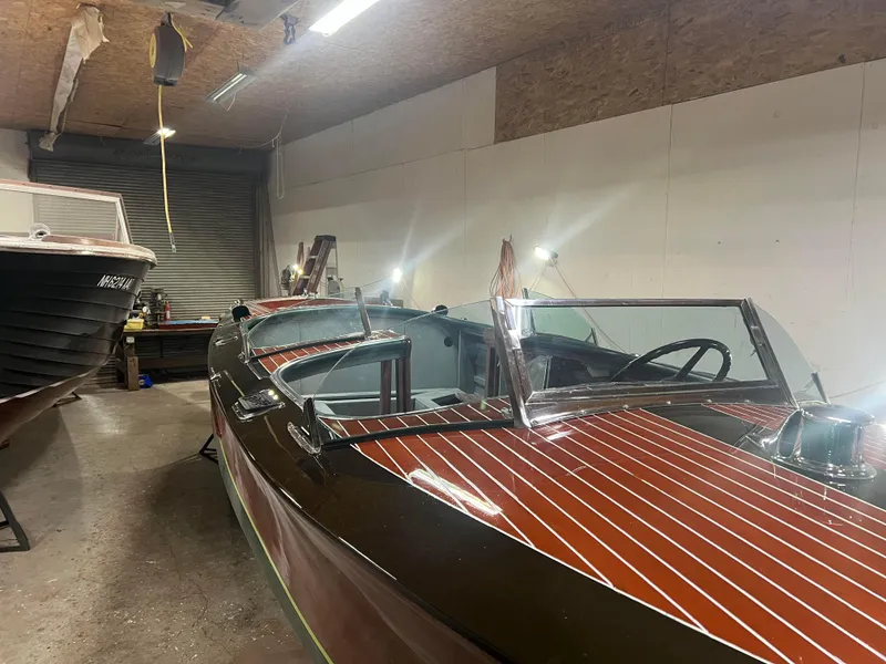 Slide: The Image of 1997 Hacker-Craft 26' Runabout in a garage, showcasing classic wooden design and sleek lines. - 6