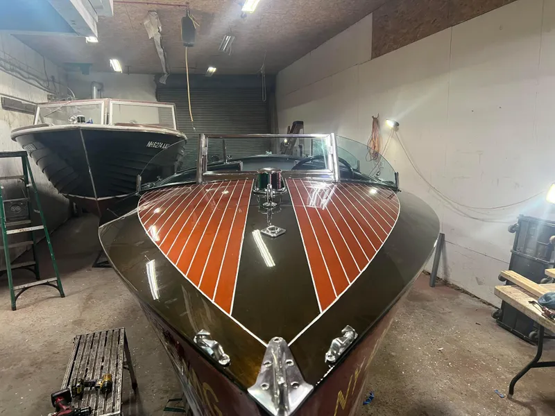 Slide: The Image of 1997 Hacker-Craft 26' Runabout in a workshop, showcasing polished wooden deck. - 7