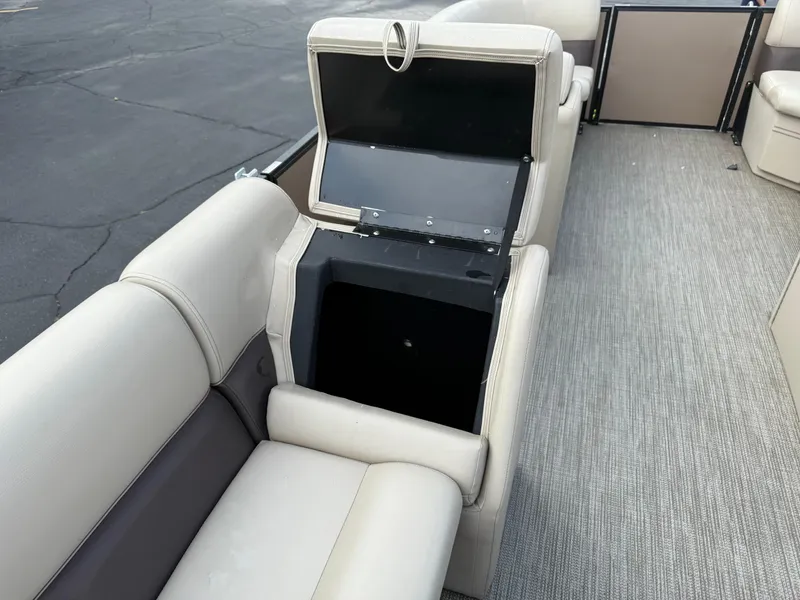 Slide: The Image of 2023 Bentley Pontoons LE 200 interior with open storage compartment, beige seating, and carpeted floor. - 18