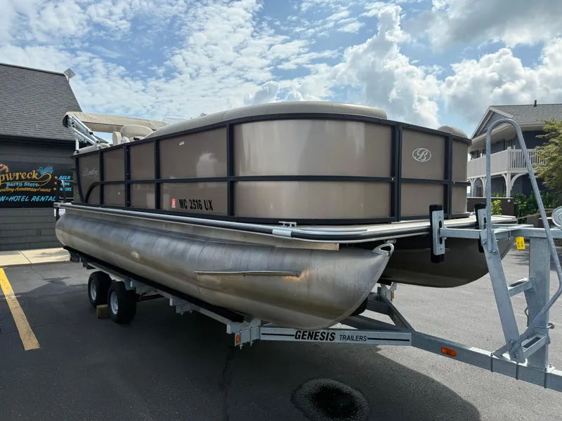 Slide: The Image of 2023 Bentley Pontoons LE 200 on Genesis trailer, parked outdoors under cloudy sky. - 4