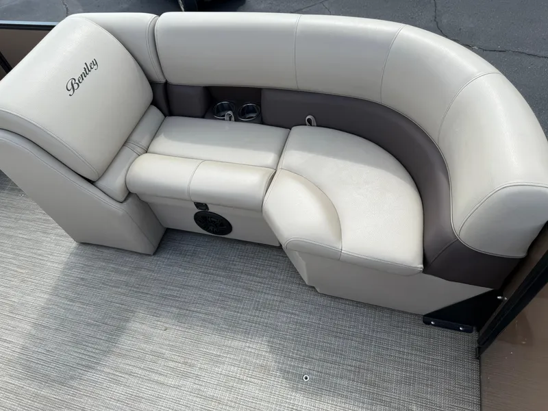 Slide: The Image of 2023 Bentley Pontoons LE 200 seating area with beige upholstery and cup holders. - 7