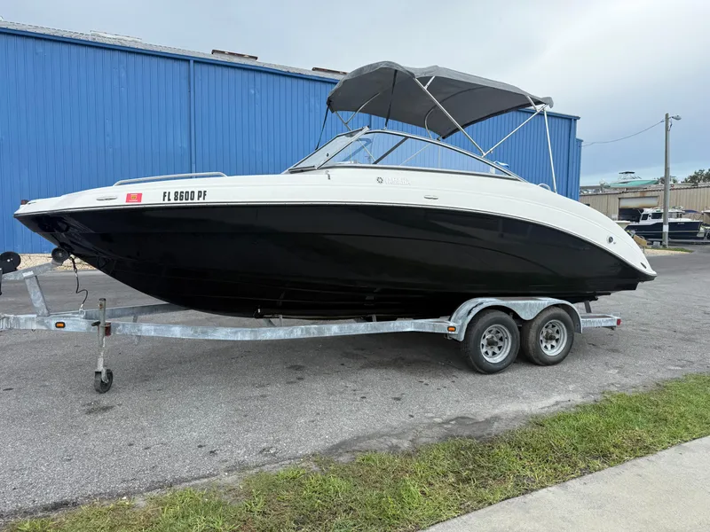The Image of 2011 Yamaha SX240 HO boat on trailer, parked near blue building. - 1