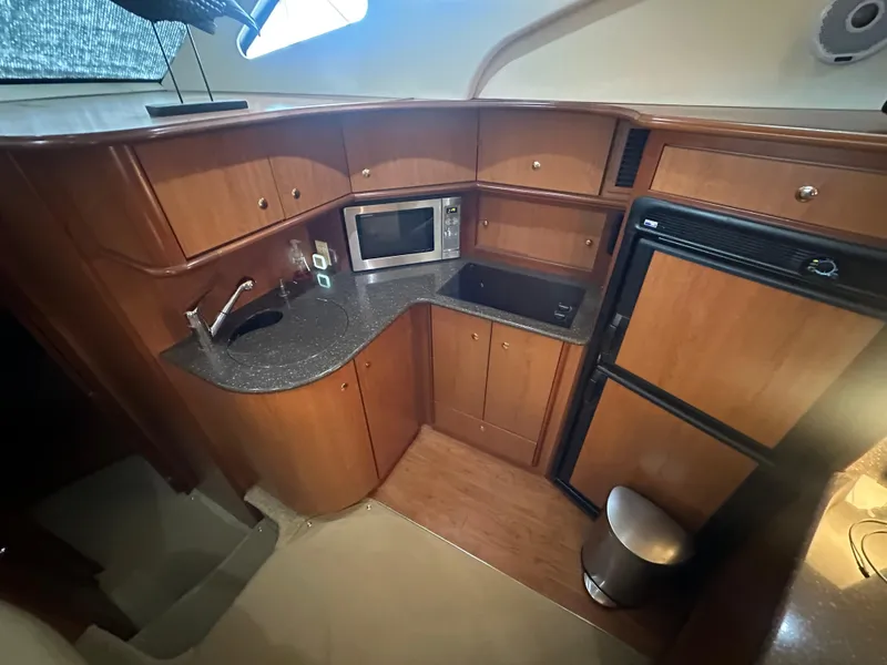Slide: The Image of 2008 Silverton 35 Motor Yacht kitchen with wood cabinets, microwave, sink, and refrigerator. - 24