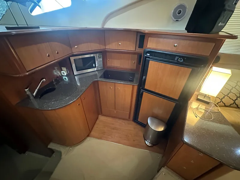 Slide: The Image of 2008 Silverton 35 Motor Yacht kitchen with wood cabinets, microwave, fridge, and sink. - 26