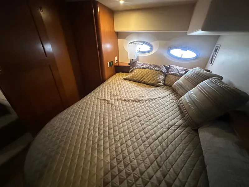 Slide: The Image of Cozy bedroom interior of 2008 Silverton 35 Motor Yacht with quilted bedding and porthole windows. - 43