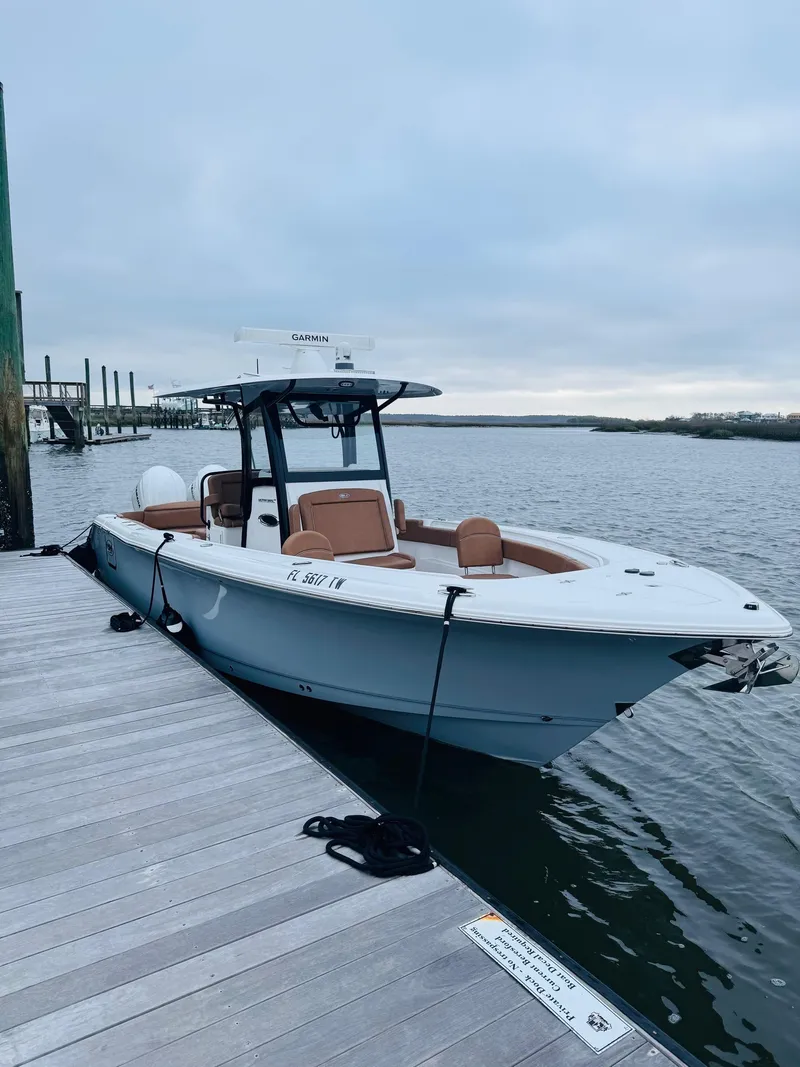 Slide: The Image of 2024 Sea Hunt Ultra 305 SE boat docked on a calm waterfront. - 10