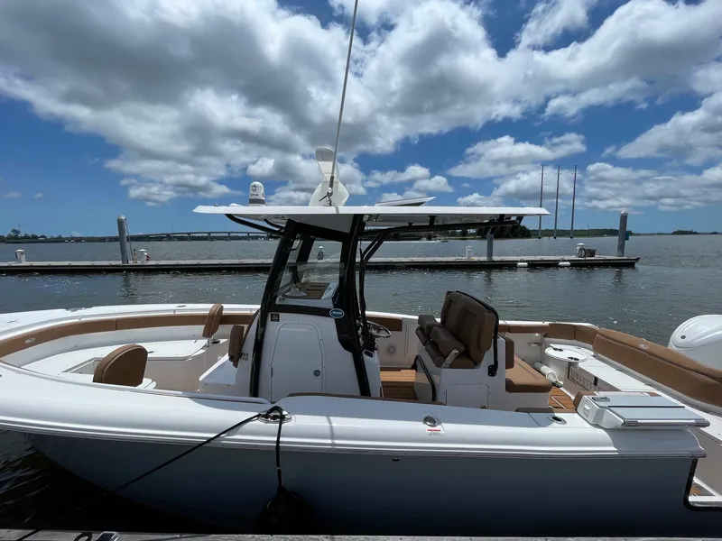 Slide: The Image of 2024 Sea Hunt Ultra 305 SE boat docked under a partly cloudy sky. - 11