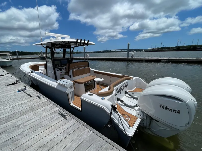 Slide: The Image of 2024 Sea Hunt Ultra 305 SE boat docked, featuring twin Yamaha engines under a partly cloudy sky. - 12
