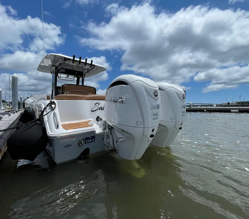 Slide: The Image of 2024 Sea Hunt Ultra 305 SE boat with twin Yamaha outboard engines docked under a cloudy sky. - 13