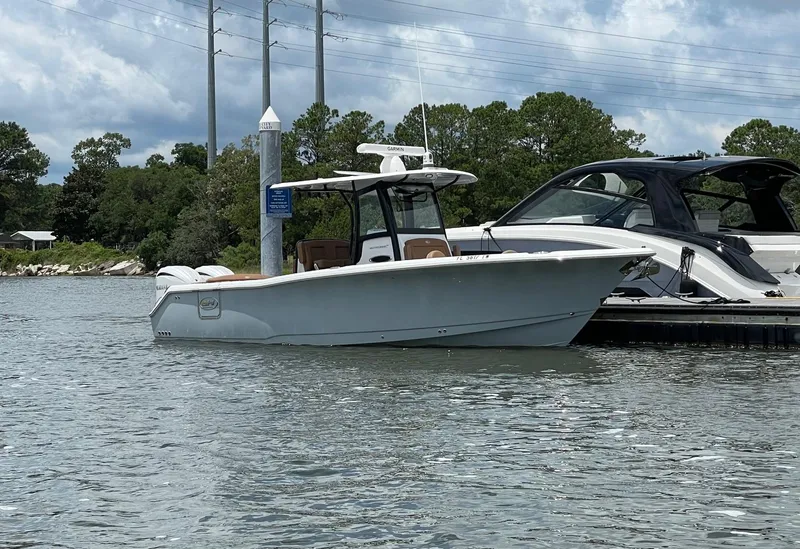 Slide: The Image of 2024 Sea Hunt Ultra 305 SE boat docked on a calm waterway. - 2