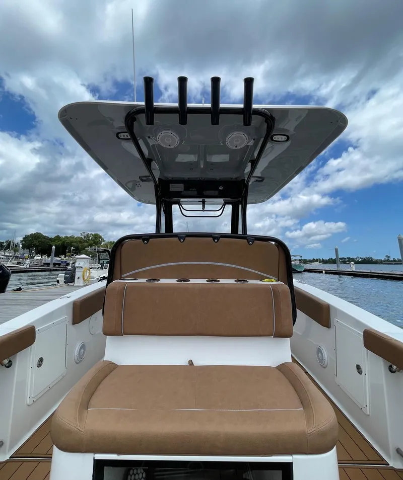 Slide: The Image of 2024 Sea Hunt Ultra 305 SE boat interior with cushioned seating and T-top under cloudy sky. - 34