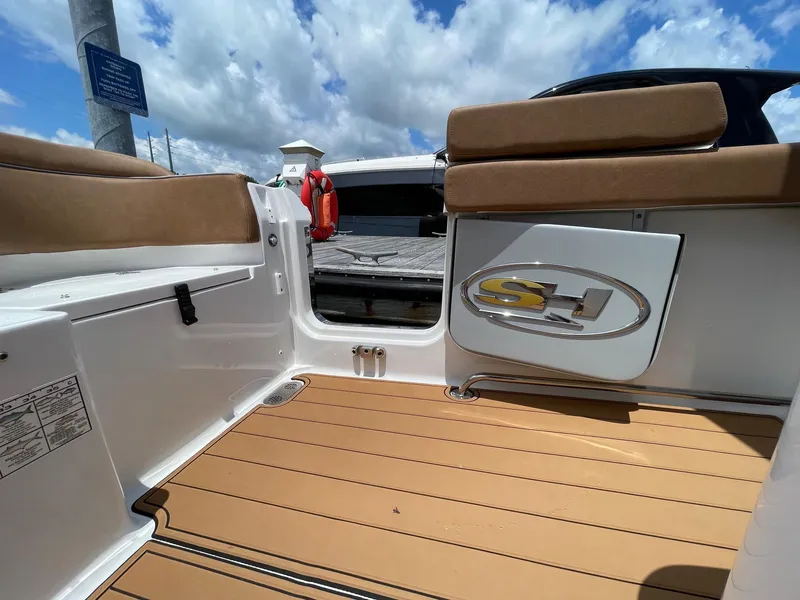 Slide: The Image of 2024 Sea Hunt Ultra 305 SE boat interior with tan seating and logo, under a cloudy sky. - 36
