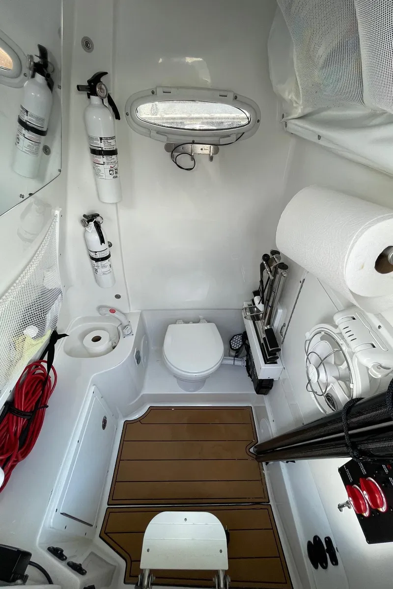 Slide: The Image of 2024 Sea Hunt Ultra 305 SE boat interior with toilet, fire extinguishers, and storage compartments. - 41