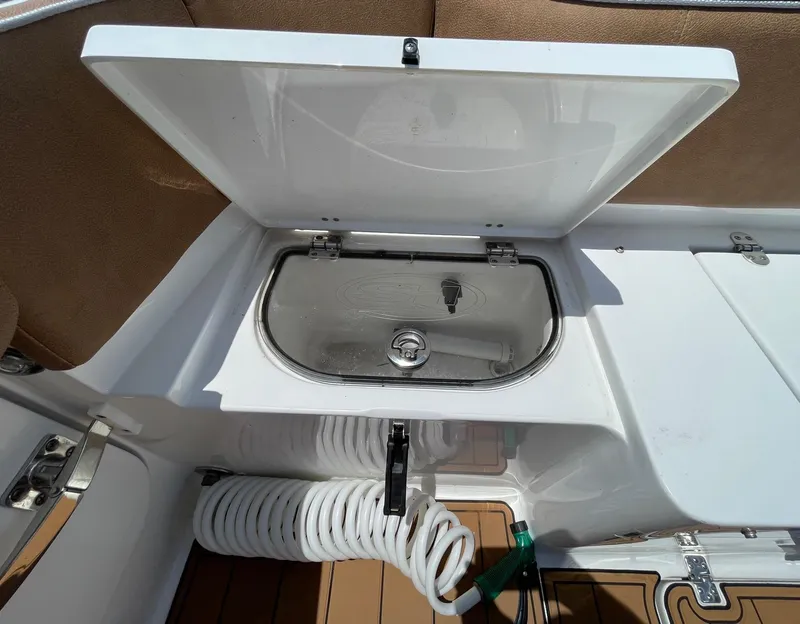 Slide: The Image of 2024 Sea Hunt Ultra 305 SE boat with open storage compartment and coiled hose. - 44
