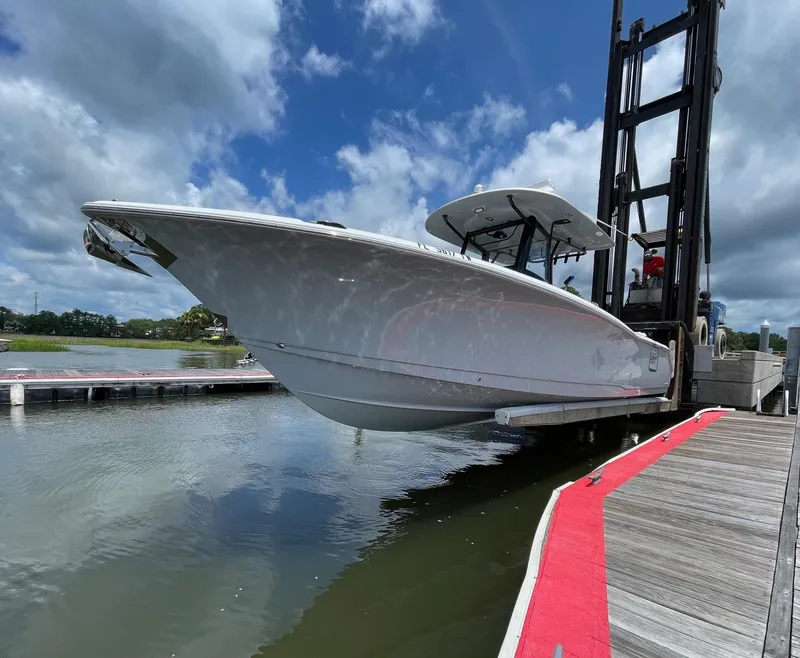Slide: The Image of 2024 Sea Hunt Ultra 305 SE boat lifted at dockside under cloudy sky. - 6