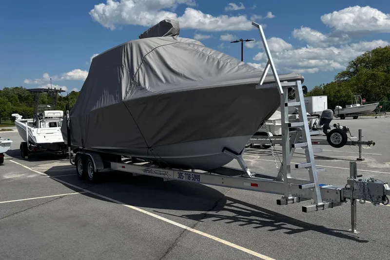 Slide: The Image of 2024 Sea Hunt Ultra 305 SE boat covered on trailer in parking lot under blue sky. - 8