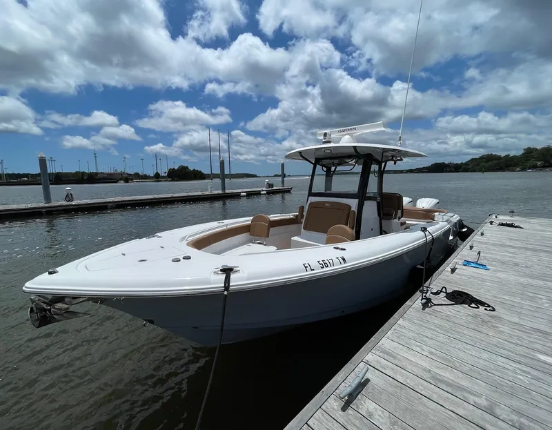 Slide: The Image of 2024 Sea Hunt Ultra 305 SE boat docked on a sunny day with cloudy sky. - 9