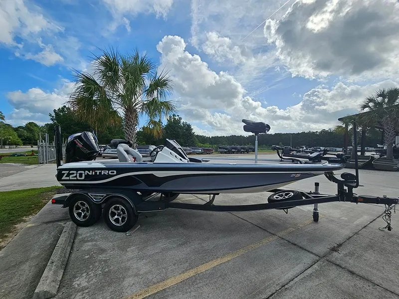 Slide: The Image of 2023 Nitro Z20 Pro boat on trailer, parked near palm trees under a cloudy sky. - 6