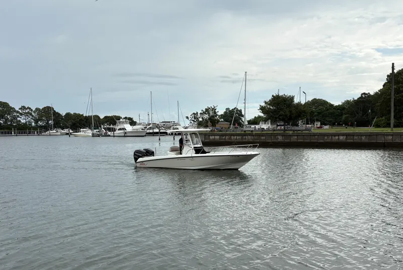 Slide: The Image of 2017 Boston Whaler 270 Dauntless boat on calm water near marina with trees in background. - 15