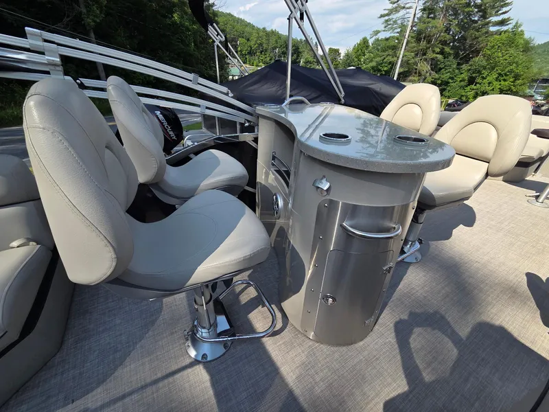 Slide: The Image of Luxury seating and table on a 2018 South Bay 523 pontoon boat, surrounded by nature. - 11