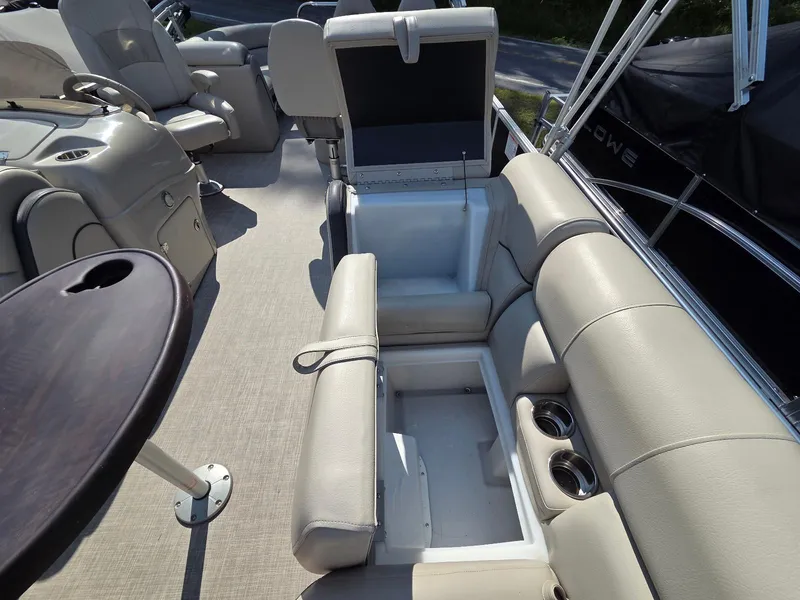 Slide: The Image of 2018 South Bay 523 boat interior with beige seating, storage compartments, and cup holders. - 18