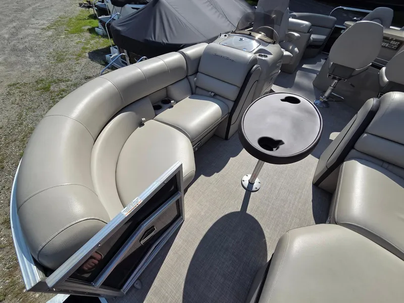 Slide: The Image of 2018 South Bay 523 pontoon boat interior with beige seating and round table. - 5